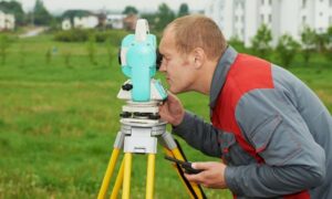 Professional land surveyor using surveying equipment during land surveys for a property development project